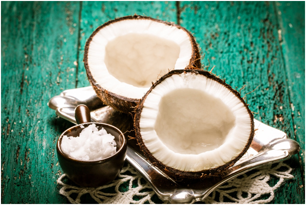 Open coconut and coconut flakes on wooden table