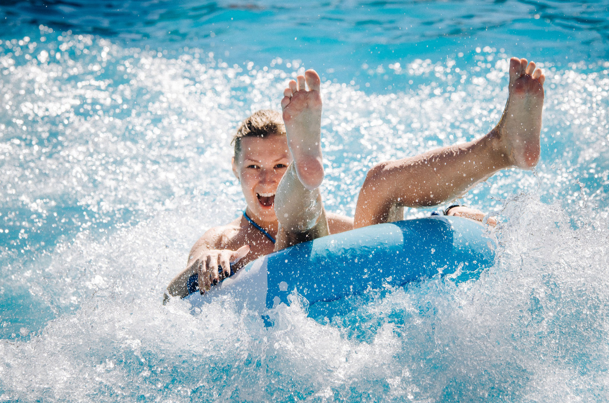 Woman sitting on an inner tube while floating through turbulent water.
