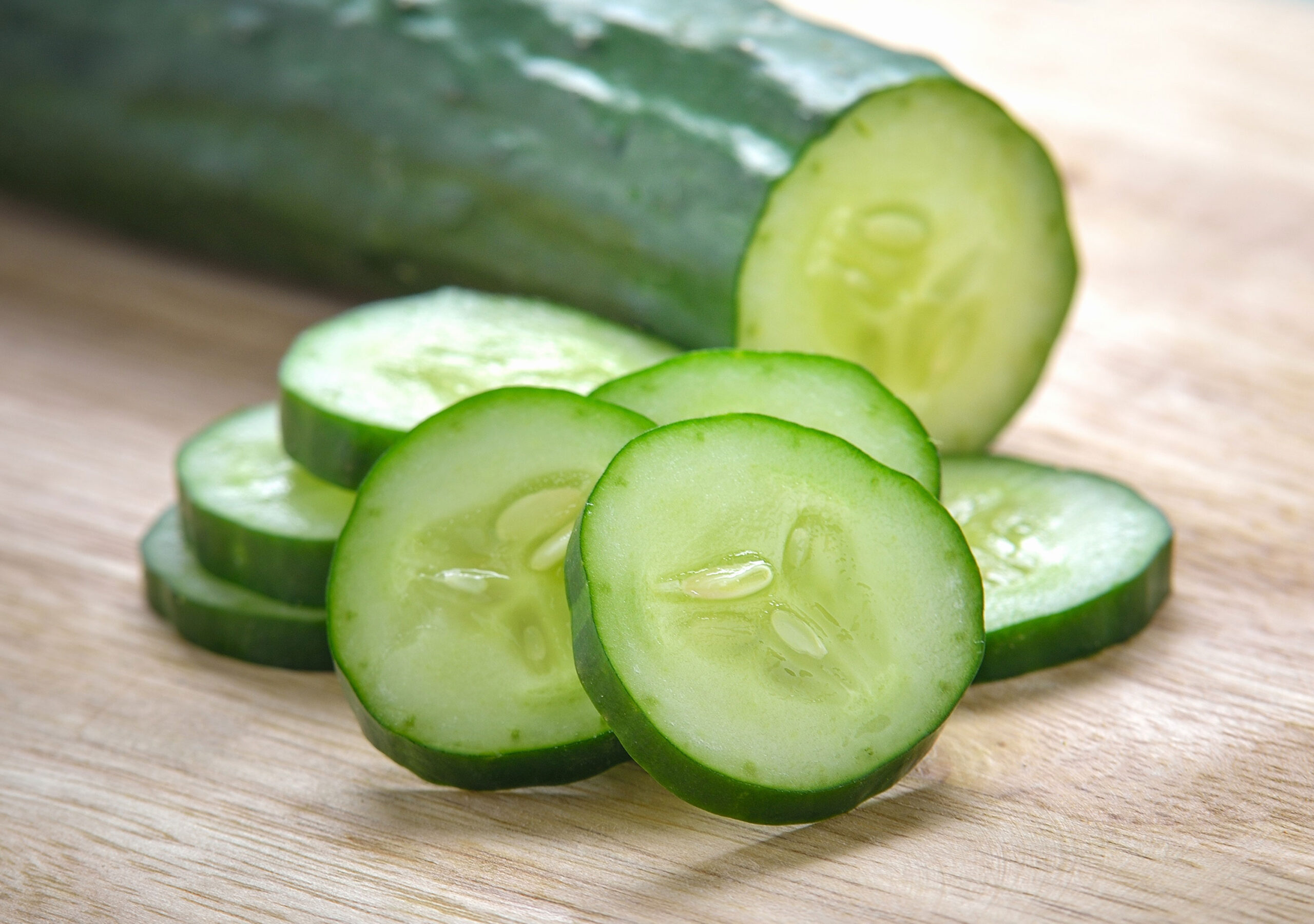 Slices of cucumber with a cucumber in the background.