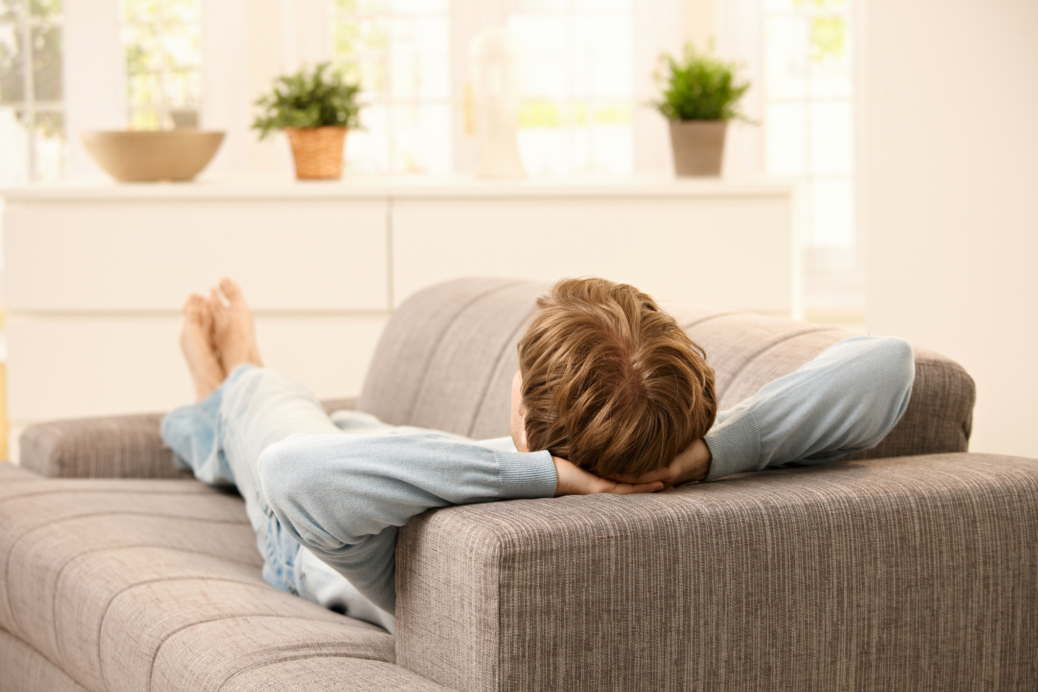 Man recovering from surgery by resting on couch.