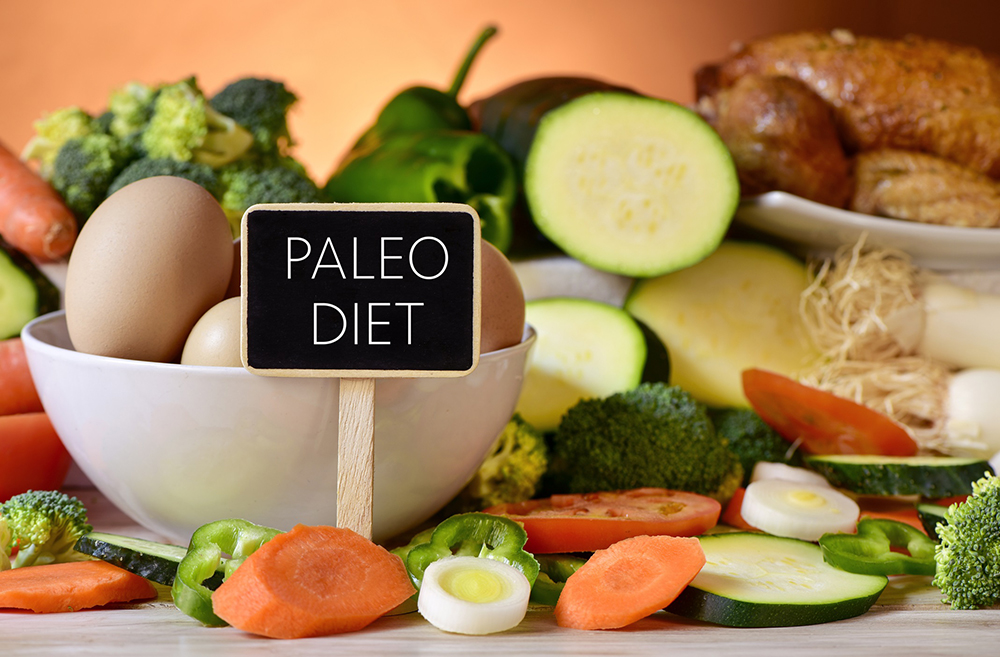 Display of eggs, carrots, tomatoes and other vegetables, with a sign reading “Paleo Diet.