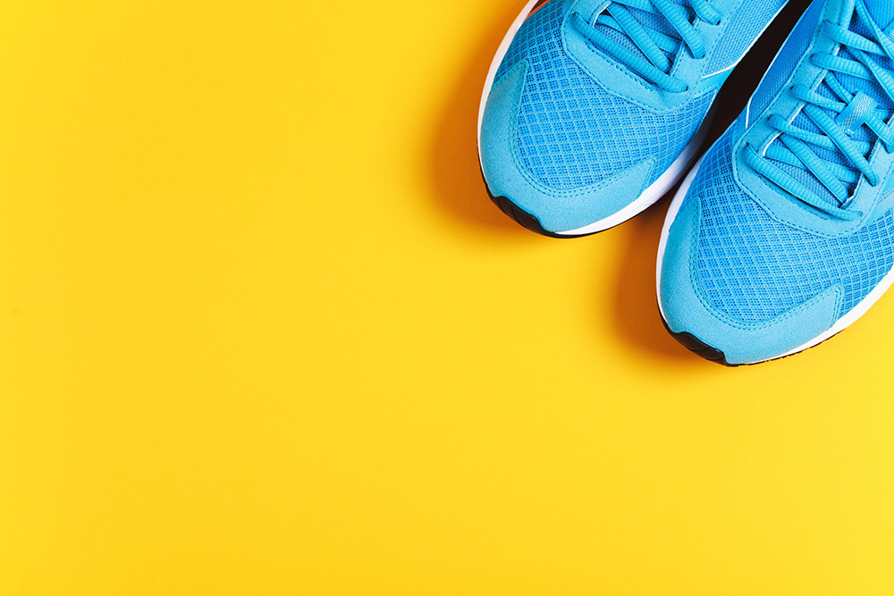 Bright blue tennis shoes on top of an orange floor.