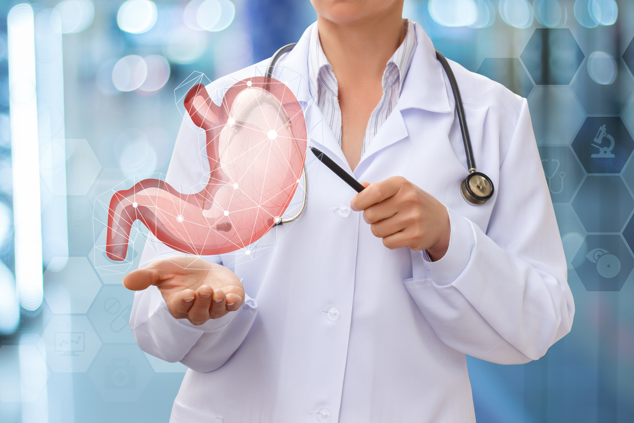 Doctor pointing towards a virtual stomach she is holding in her other hand.