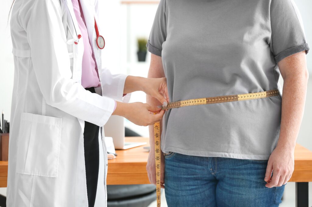 Doctor measuring overweight person’s waist to see if she qualifies for a weight loss balloon procedure.